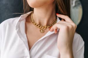 Golden bijouterie chain on woman neck. Close-up. Black background.